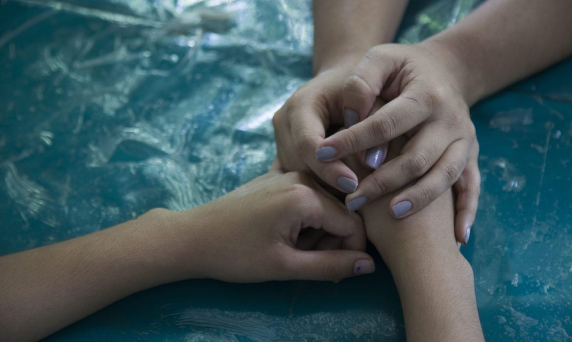 The hands of a UNICEF child protection specialist hold those of a girl who has been targeted by a gang member, San Marcos, El Salvador.