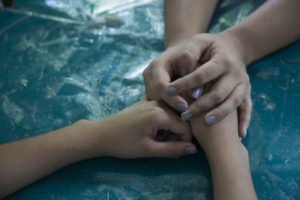The hands of a UNICEF child protection specialist hold those of a girl who has been targeted by a gang member, San Marcos, El Salvador.